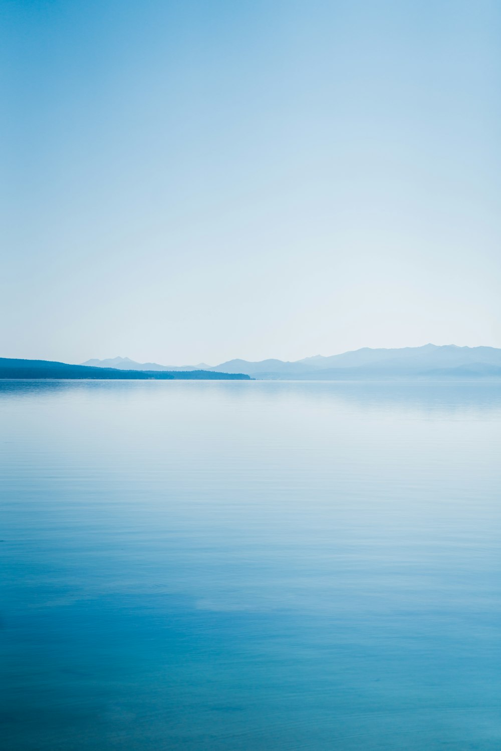 blue body of water under white sky during daytime