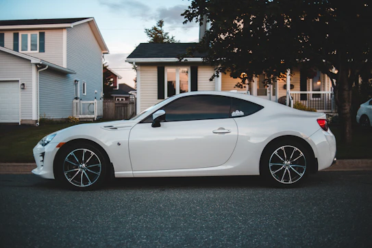 white porsche 911 parked near green tree during daytime