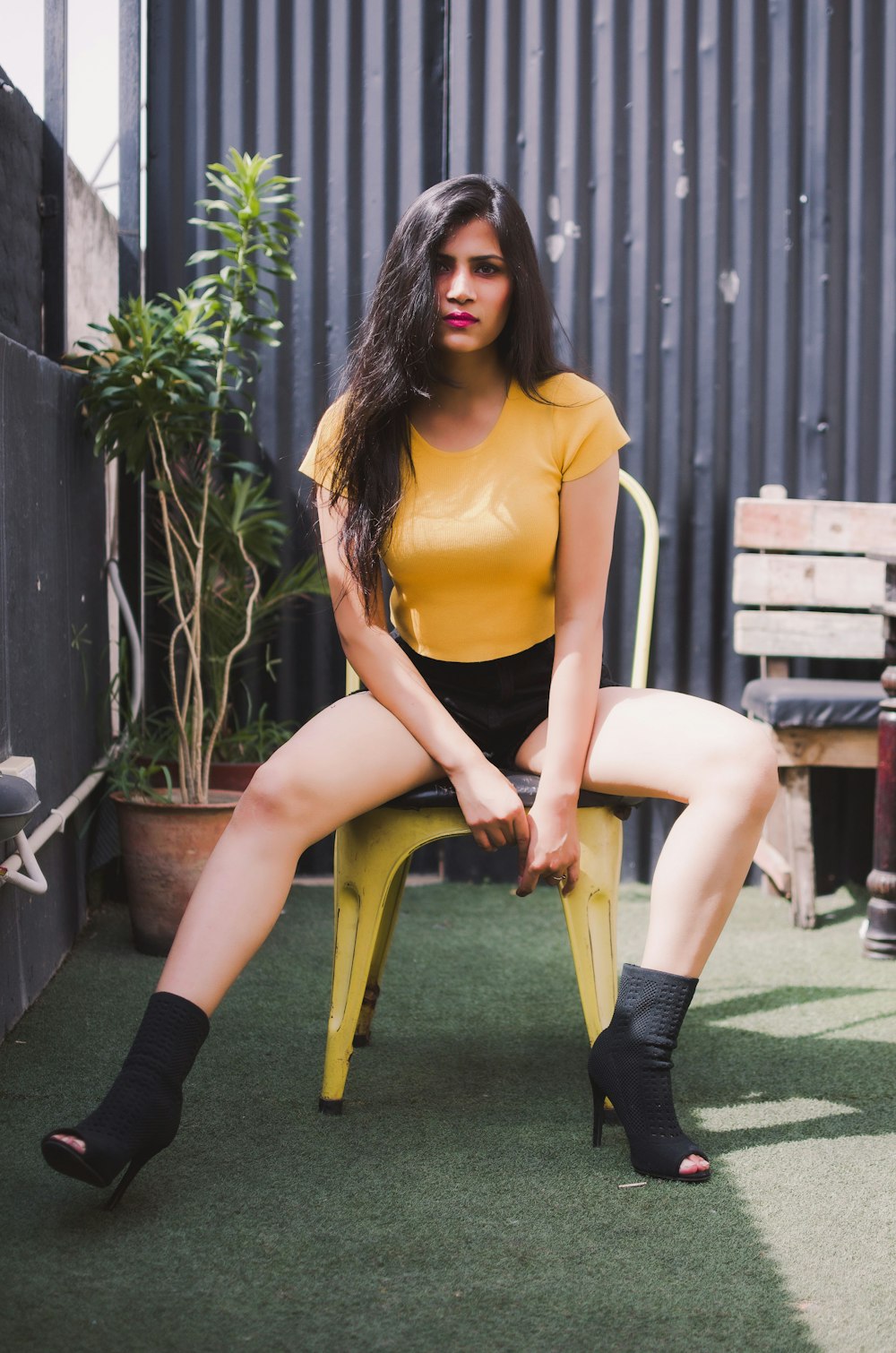 woman in yellow tank top and black leggings sitting on brown wooden bench