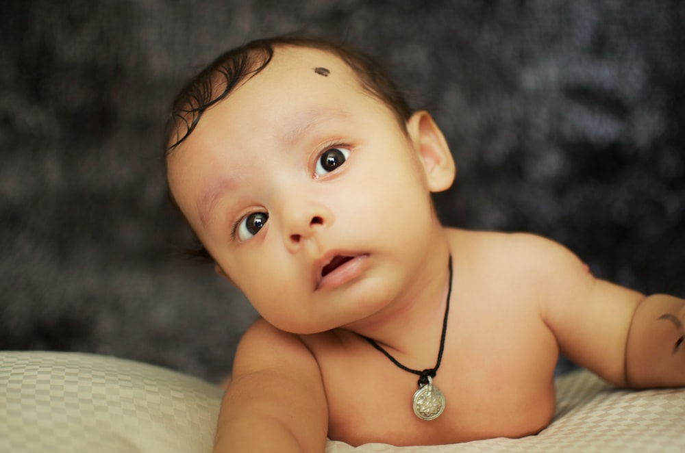 topless baby lying on bed