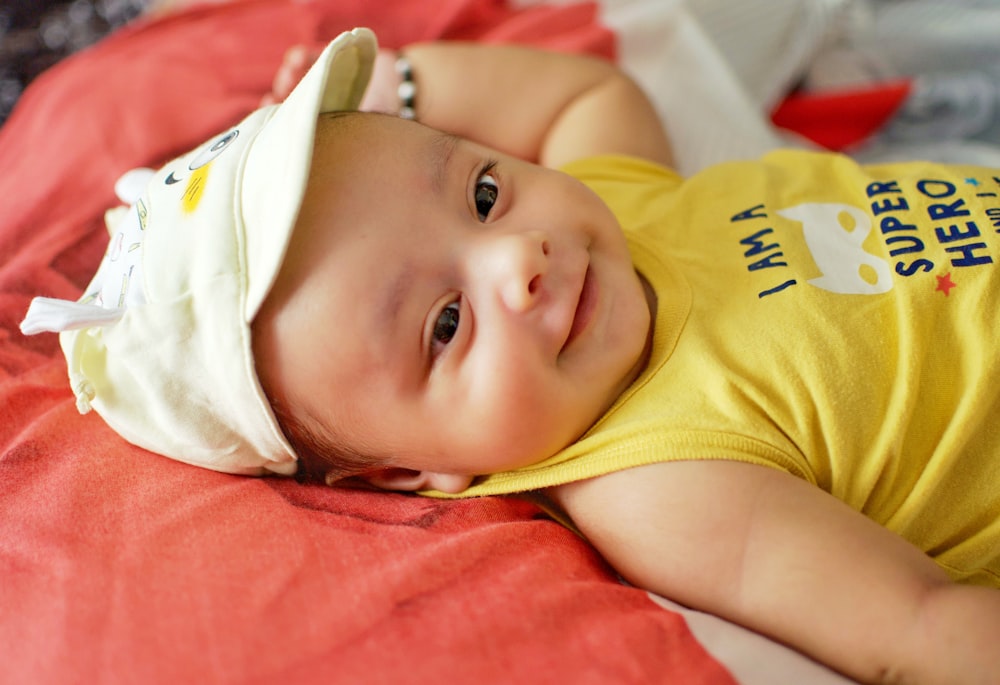 baby in yellow shirt lying on bed