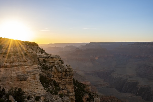 A panoramic view of a rugged canyon at golden hour with warm light casting long shadows.