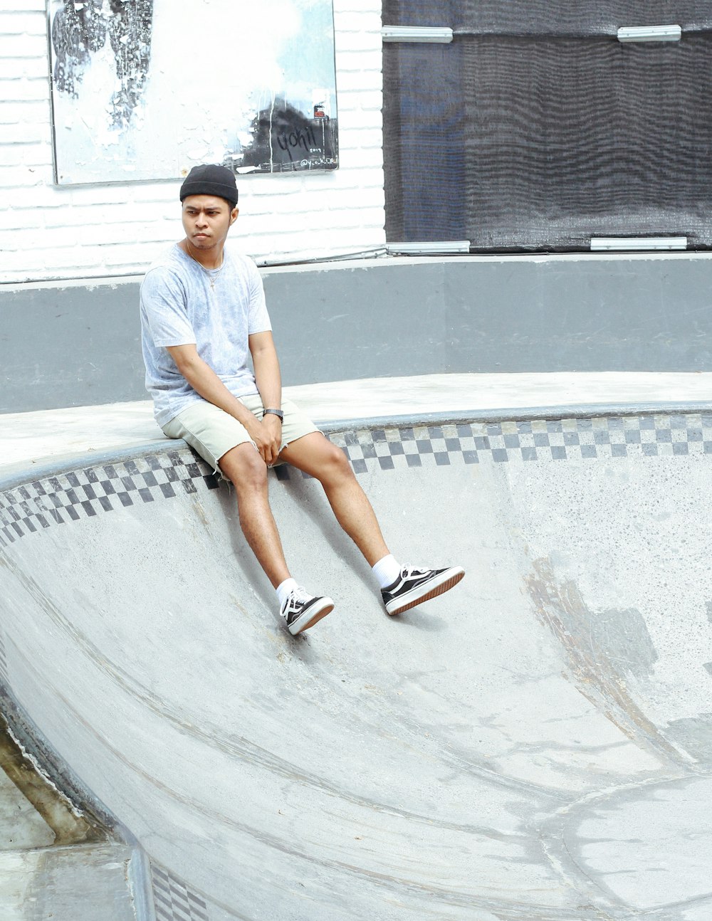 woman in white t-shirt and white shorts sitting on gray concrete floor