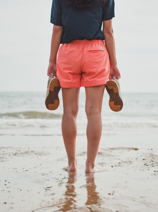 man in blue shirt and orange shorts standing on beach during daytime