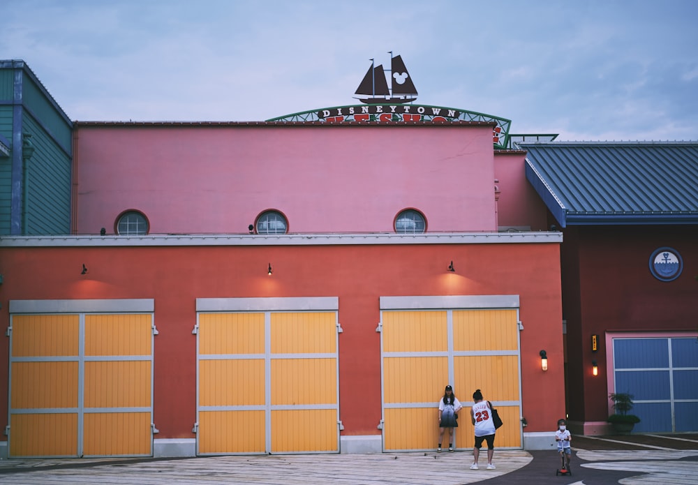 Personas de pie frente a un edificio rojo y amarillo durante el día