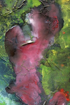 An abstract painting with swirls of red, green, and hints of blue. The textured surface features a mix of vibrant and muted tones, creating an organic pattern reminiscent of natural forms.