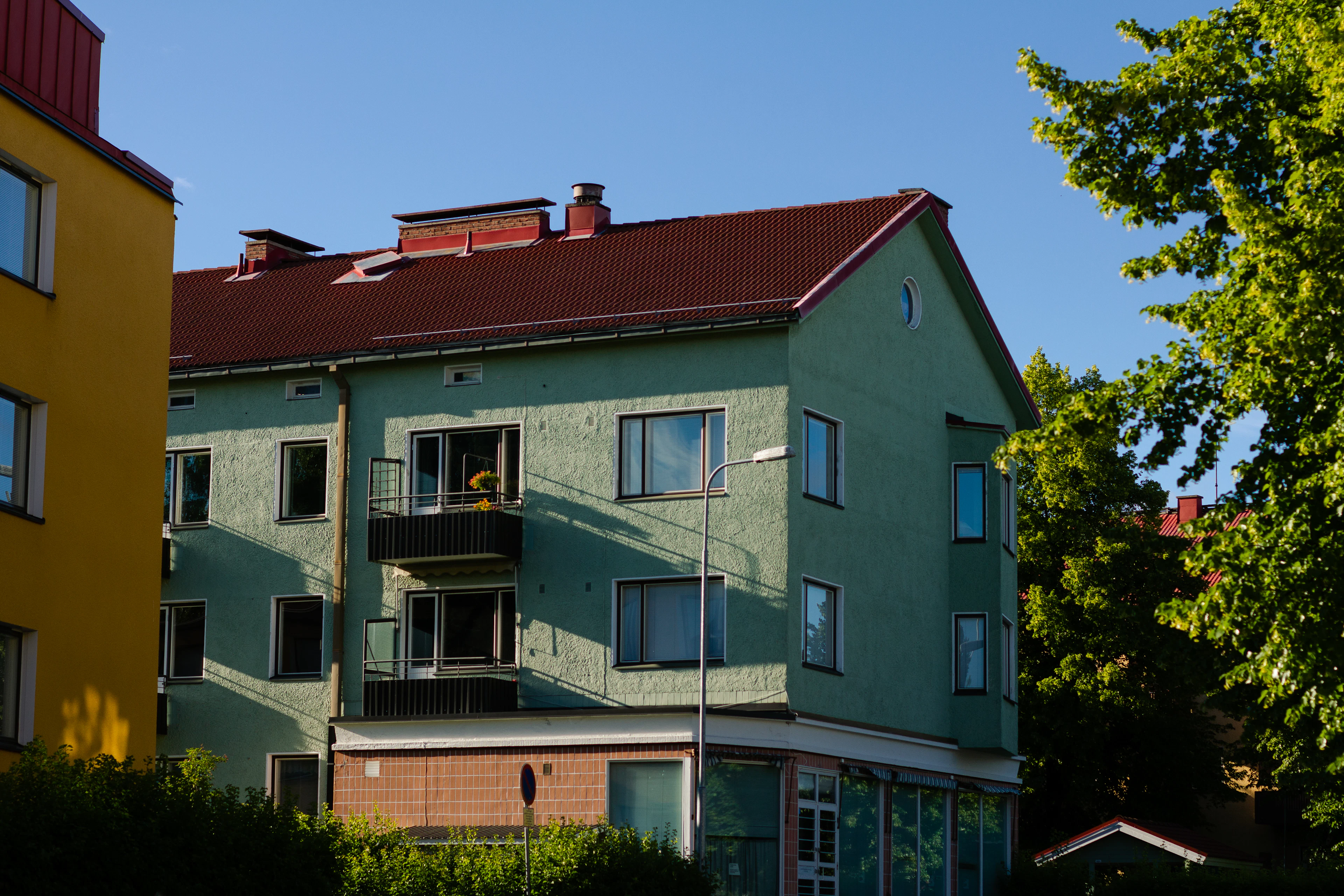 Grönt flerbostadshus med balkonger och rött tak