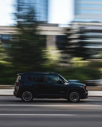 The rs76 vehicle speeding along a highway with a blurred cityscape in the background.