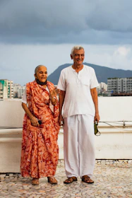 man in white polo shirt standing beside woman in orange dress