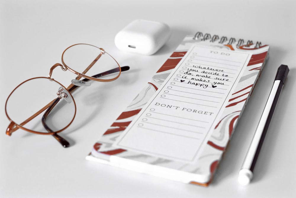 silver framed eyeglasses on white printer paper beside white apple charger