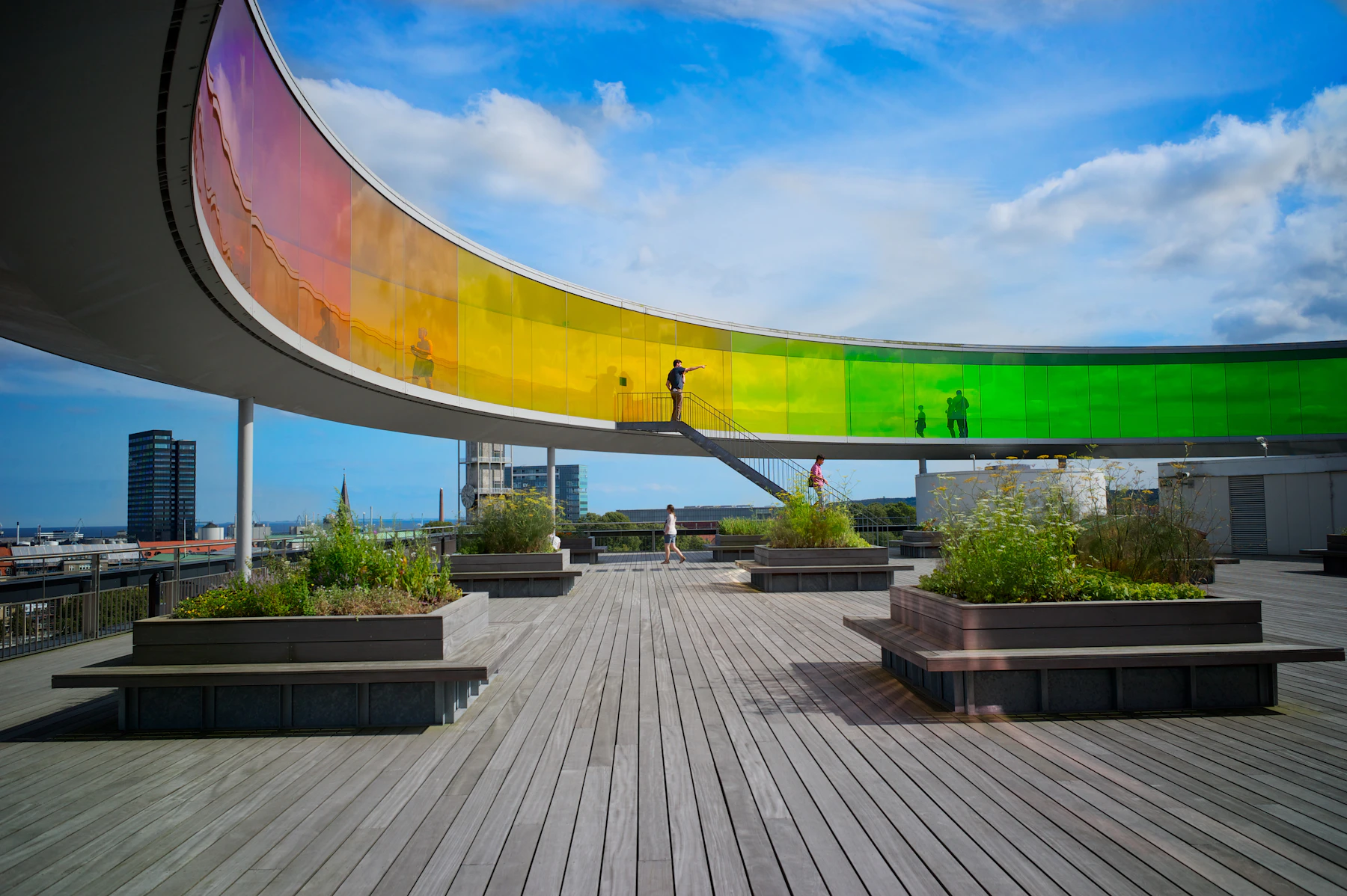 The circular rainbow walkway above ARoS overlooks an outdoor roof terrace.