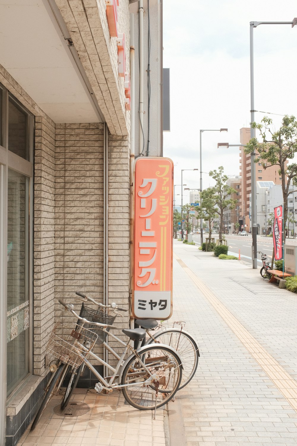 昼間、茶色のコンクリートの建物の脇に停車している白いシティバイク