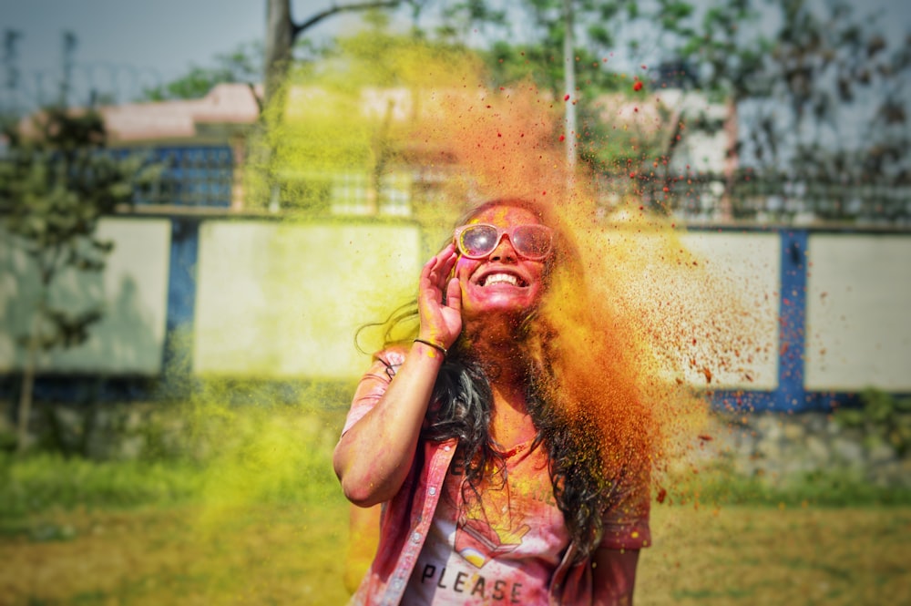 woman in pink tank top with yellow powder on her face
