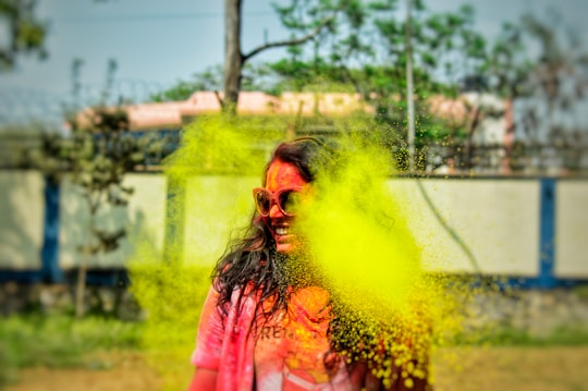 woman in pink jacket with yellow smoke on her face in Guwahati India