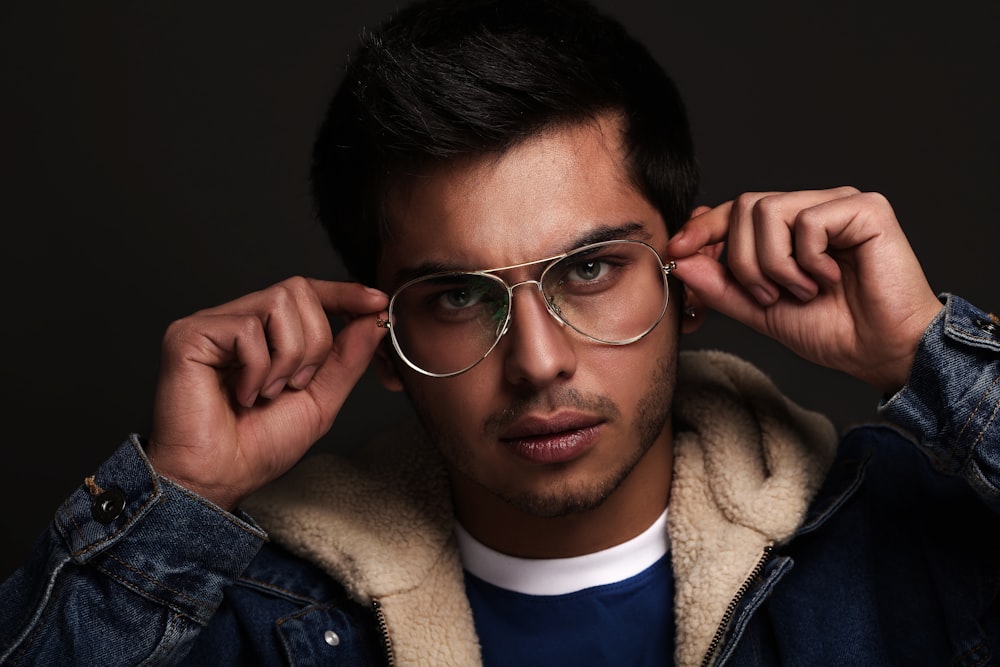 man in blue denim jacket wearing black framed eyeglasses