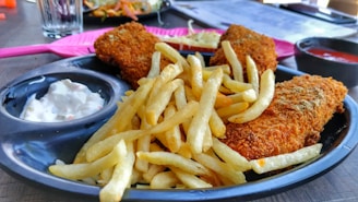 A rustic plate of golden crispy fish and chips served with lemon wedges and tartar sauce.
