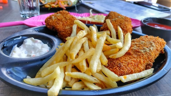 A rustic plate of golden crispy fish and chips served with lemon wedges and tartar sauce.