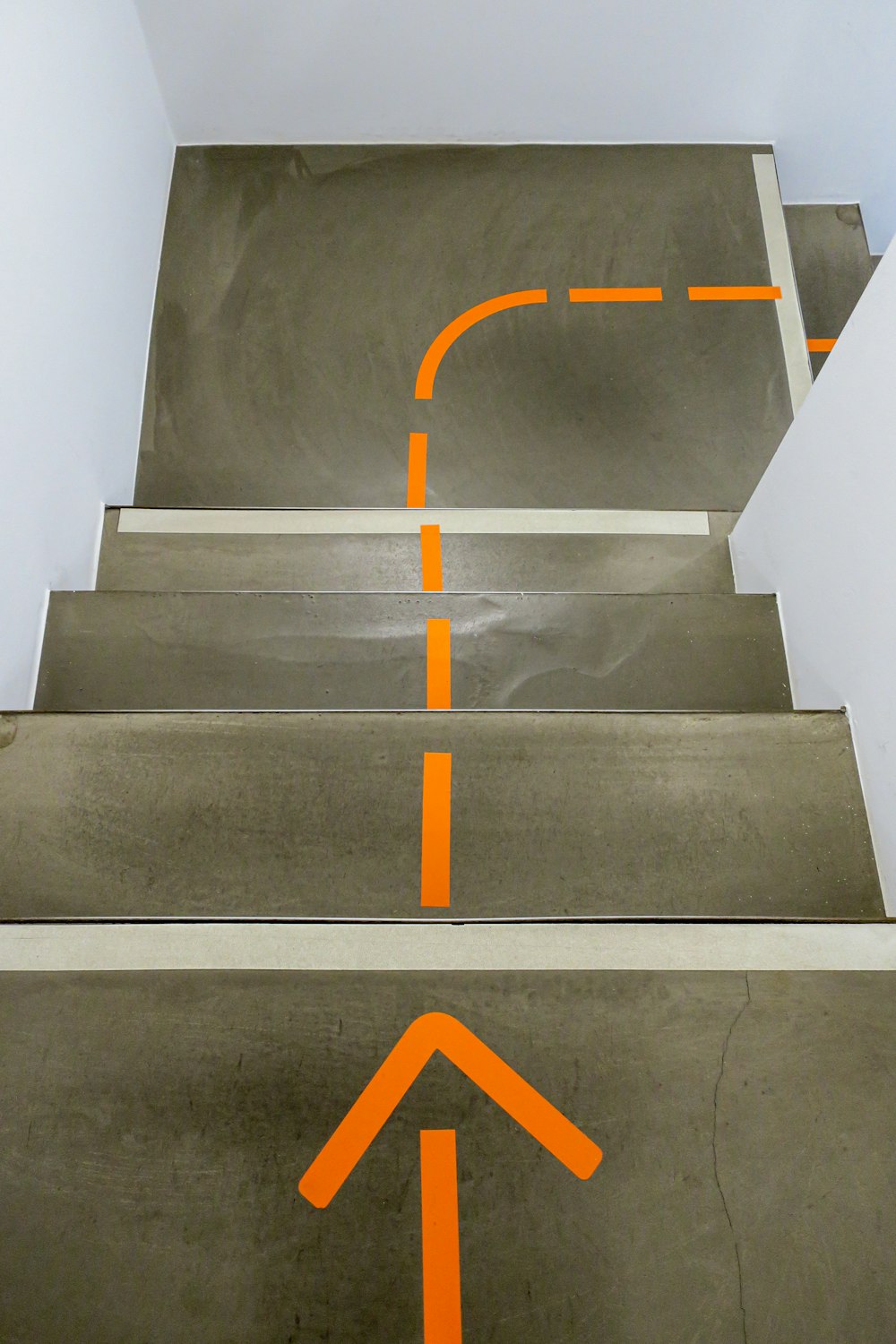 Graue Betontreppe mit gelbem Pfeilzeichen