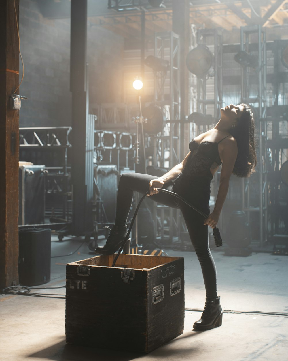 woman in black tank top and black pants standing on brown wooden box