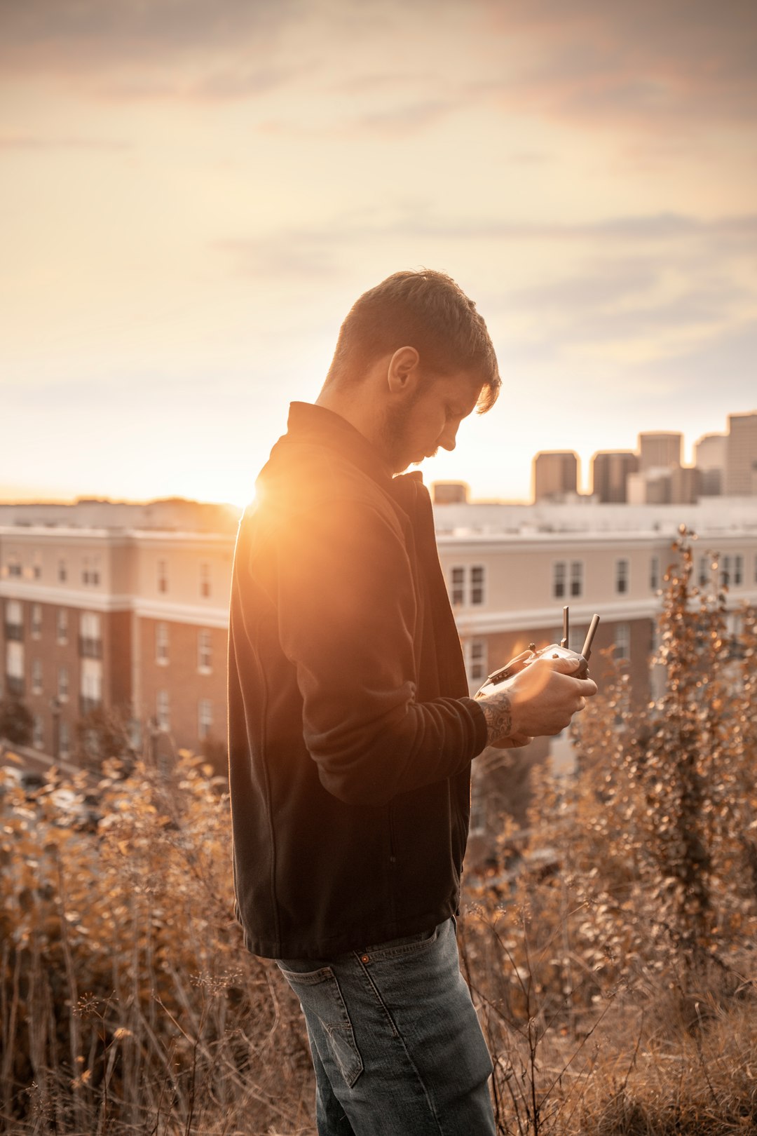 man in brown hoodie standing on the city during daytime