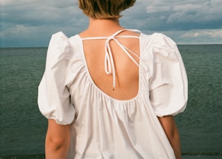 woman in white spaghetti strap top standing on beach during daytime