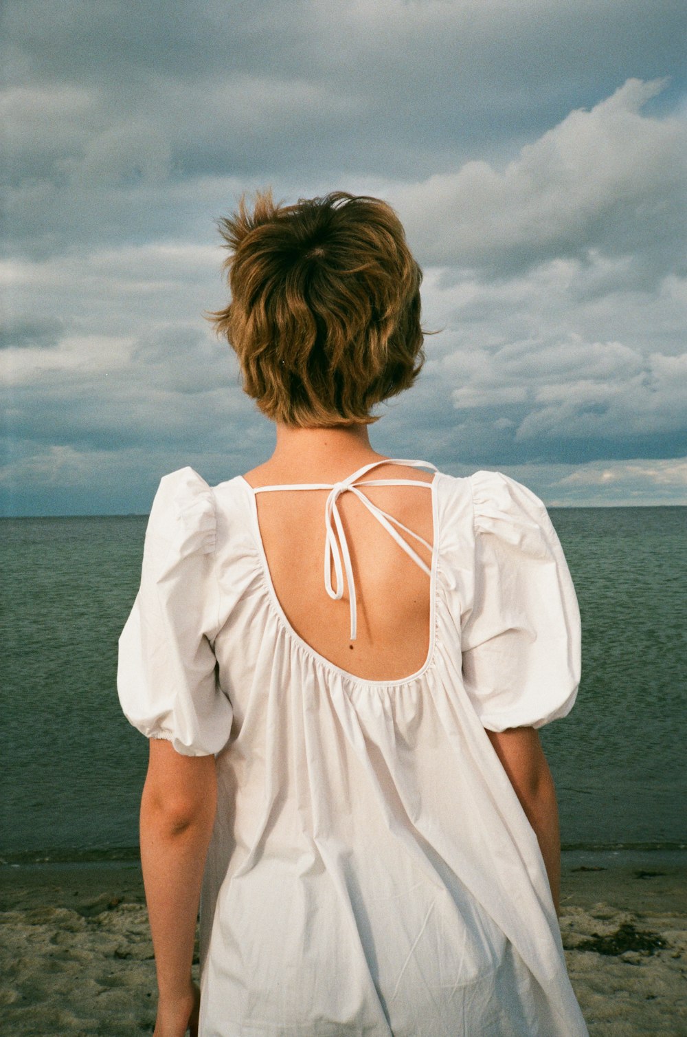 woman in white spaghetti strap top standing on beach during daytime