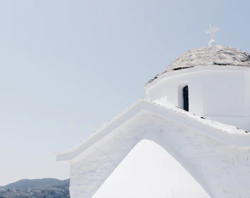 A minimalist shot of a blue-domed chapel against a clear sky, capturing Cycladic simplicity.