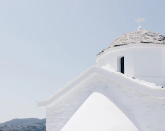 A minimalist shot of a blue-domed chapel against a clear sky, capturing Cycladic simplicity.
