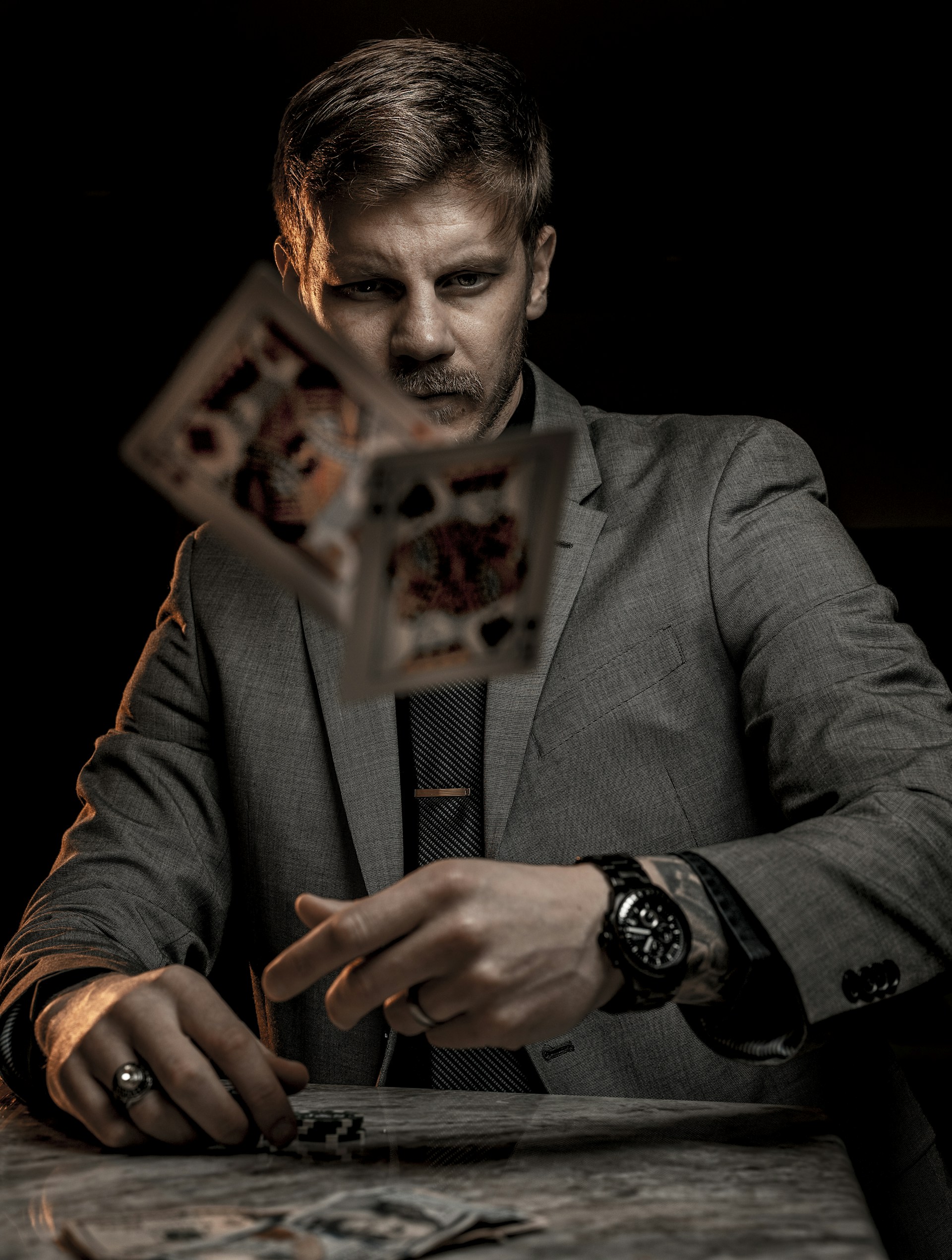 man in gray suit jacket holding jack of diamonds playing card