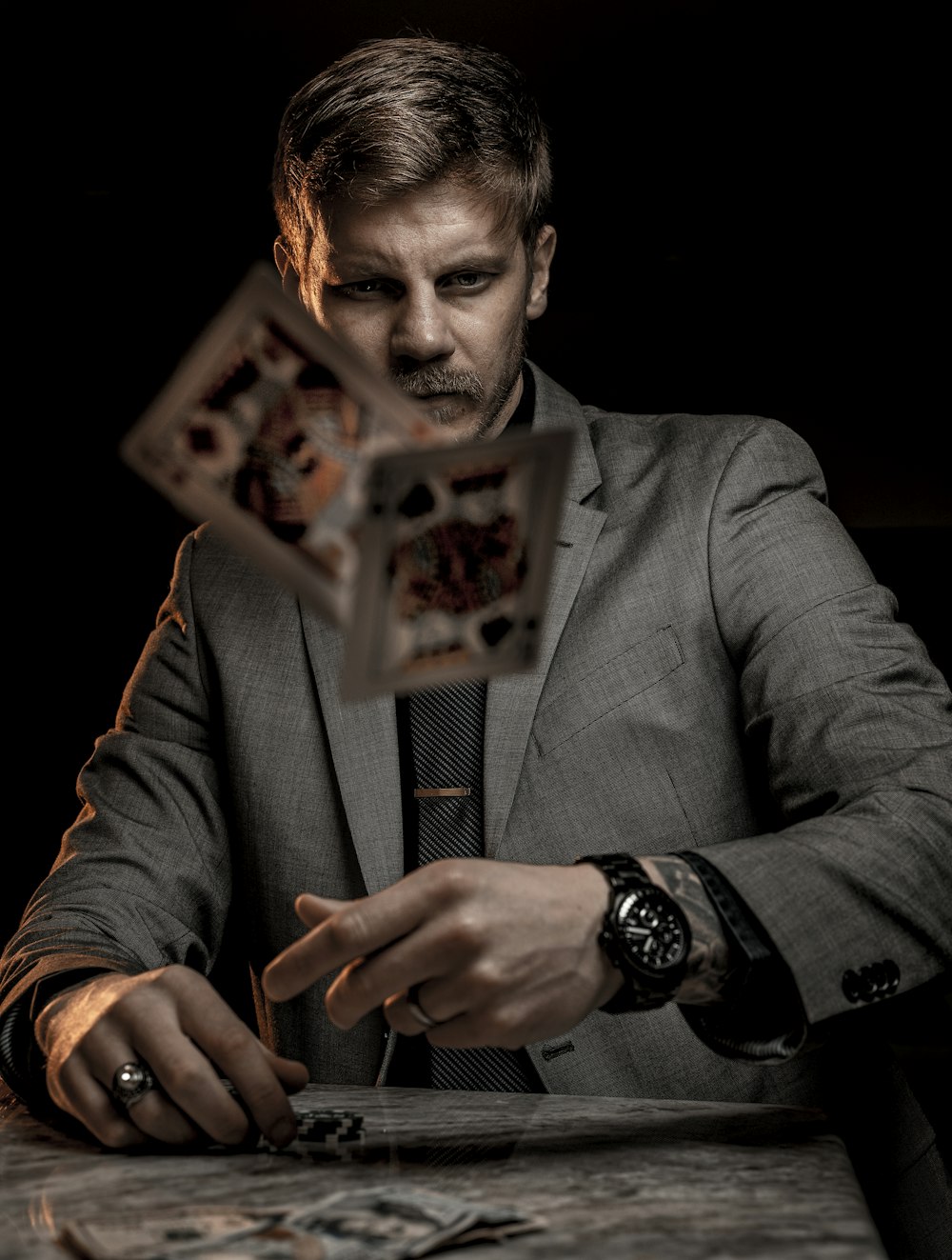 man in gray suit jacket holding jack of diamonds playing card