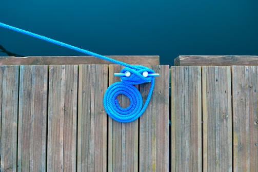A vibrant blue and orange spliced rope lead coiled neatly on a wooden table.