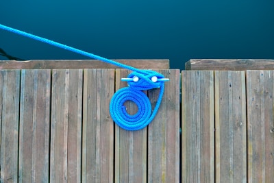 Close-up of light blue nautical ropes neatly coiled on a wooden dock