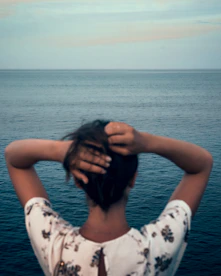 woman in white and black floral sleeveless dress covering her face with her hair
