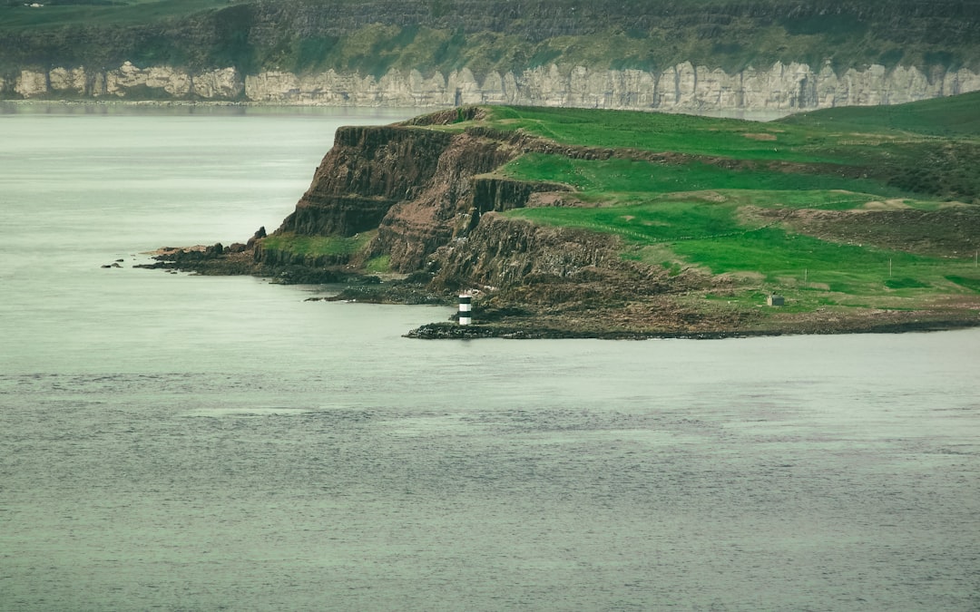 white boat on sea near green grass field during daytime