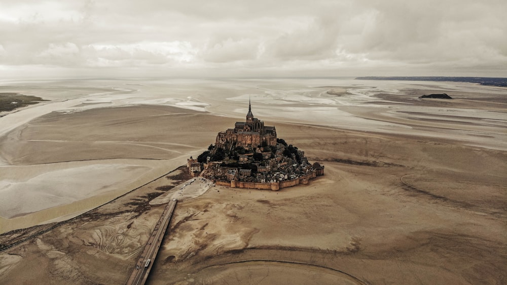 brown and black concrete building on brown sand under white clouds during daytime