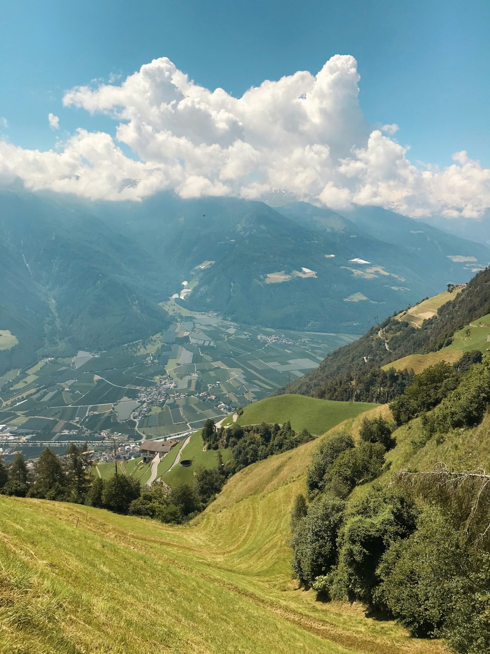 green grass field and mountains under white clouds and blue sky during daytime