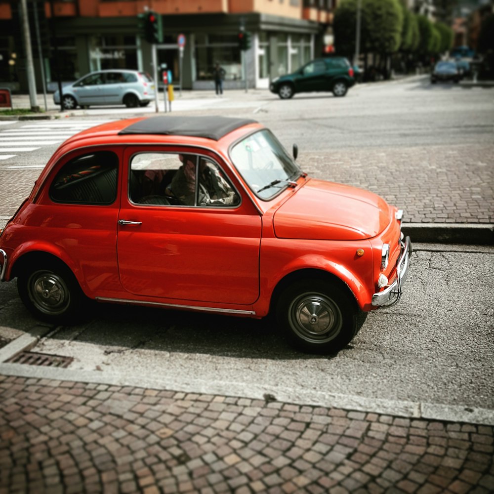 red volkswagen beetle parked on sidewalk during daytime