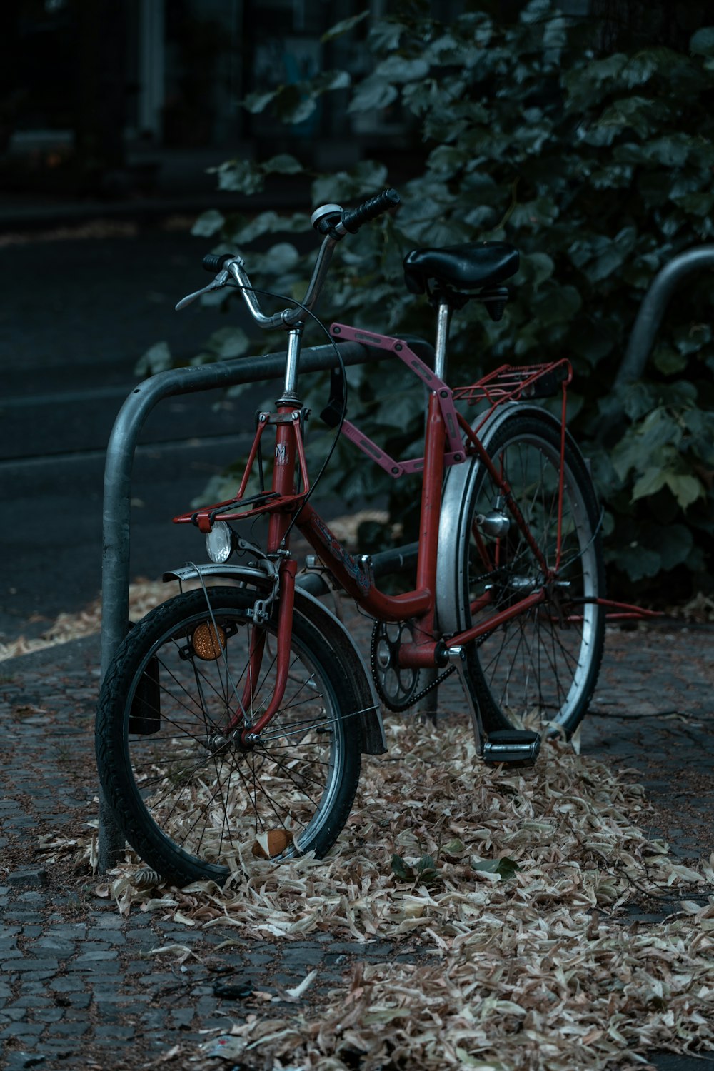 red commuter bike parked beside gray metal fence during daytime