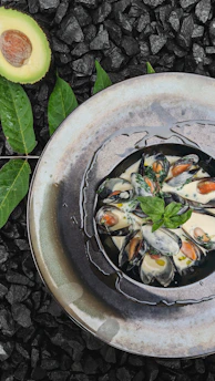 Close-up of fresh mussels arranged on a rustic wooden platter with lemon wedges.