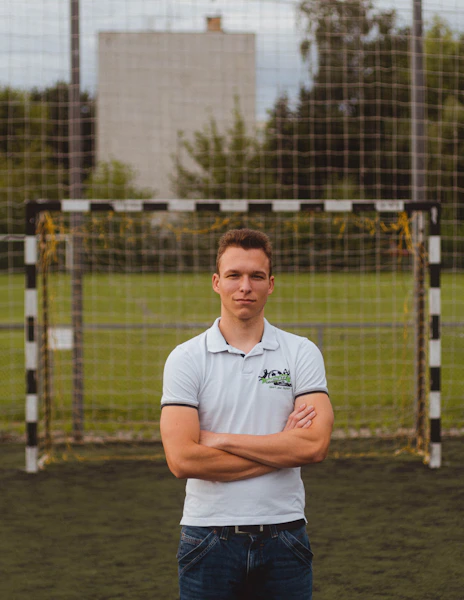 man in white polo shirt standing near fence during daytime