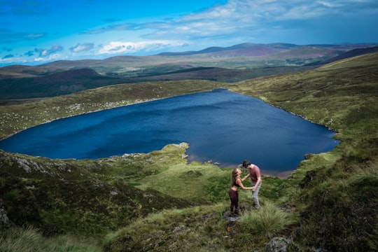 man in black shorts standing on cliff near lake during daytime in Lough Ouler Ireland
