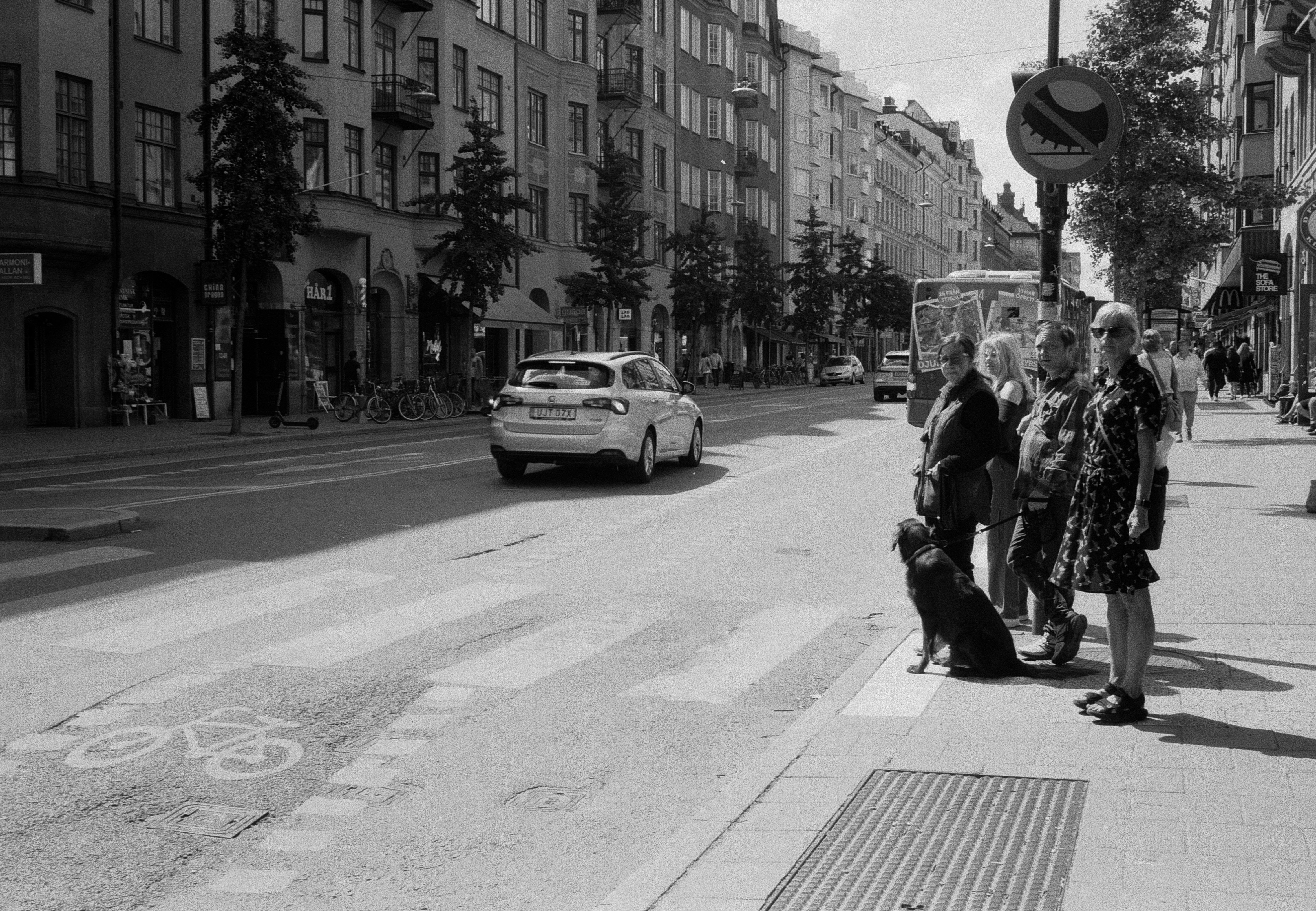 grayscale photo of man and woman sitting on bench near road