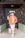 man in orange button up long sleeve shirt and black pants standing beside black wooden door