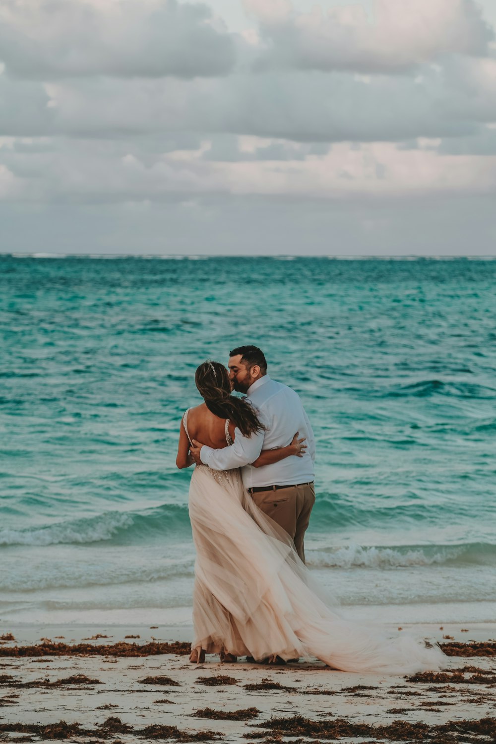 man and woman kissing on beach during daytime