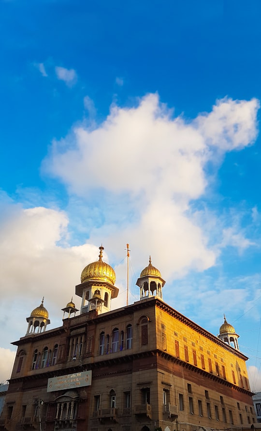 gold and white dome building under blue sky in Gurdwara Sis Ganj Sahib India