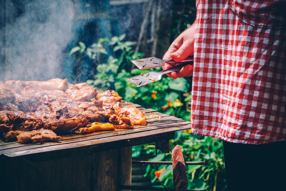 person holding knife slicing meat on brown wooden chopping board