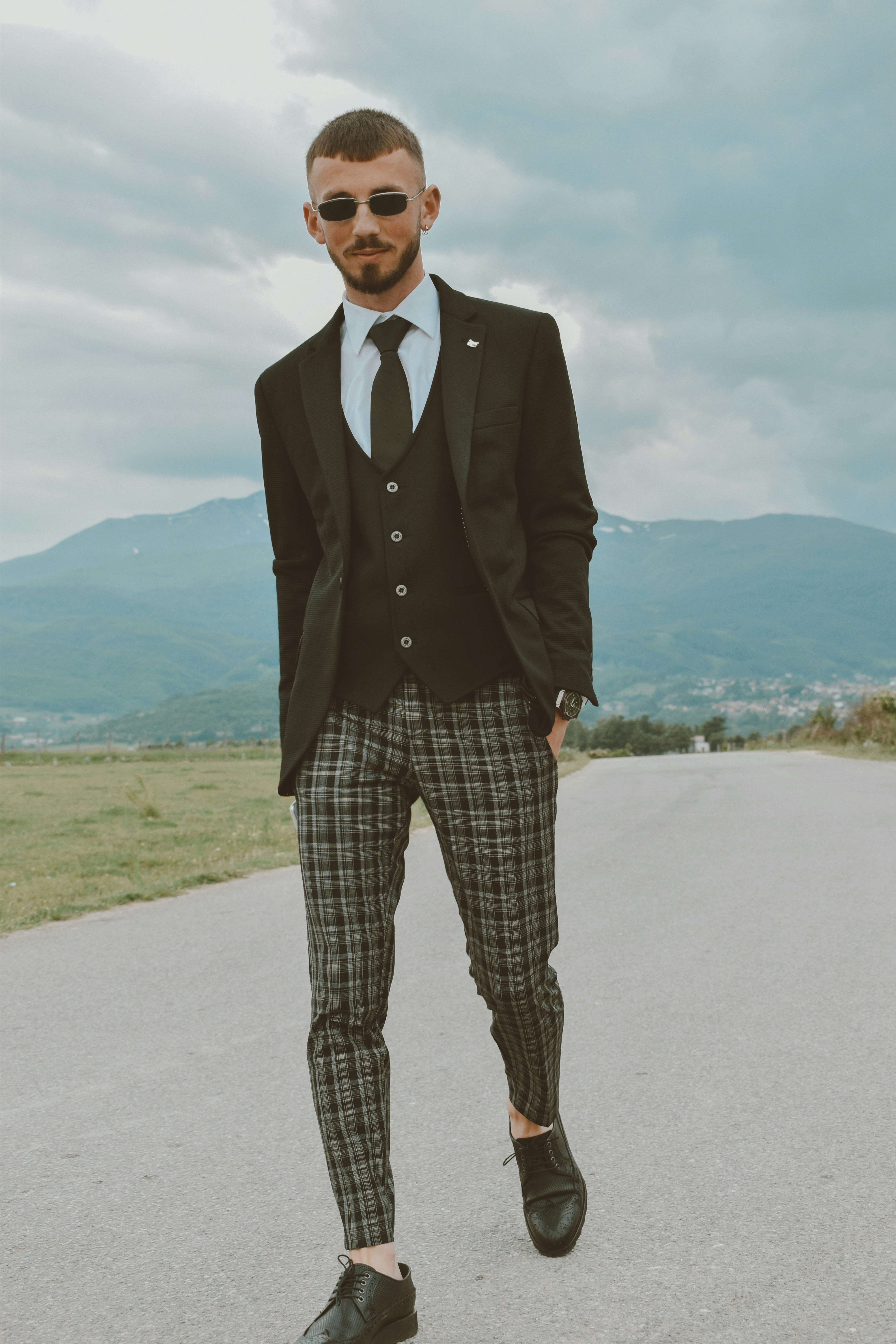 man in black suit standing on gray sand during daytime