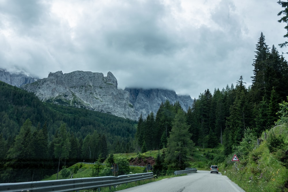 Coche negro en la carretera cerca de árboles verdes y montaña durante el día