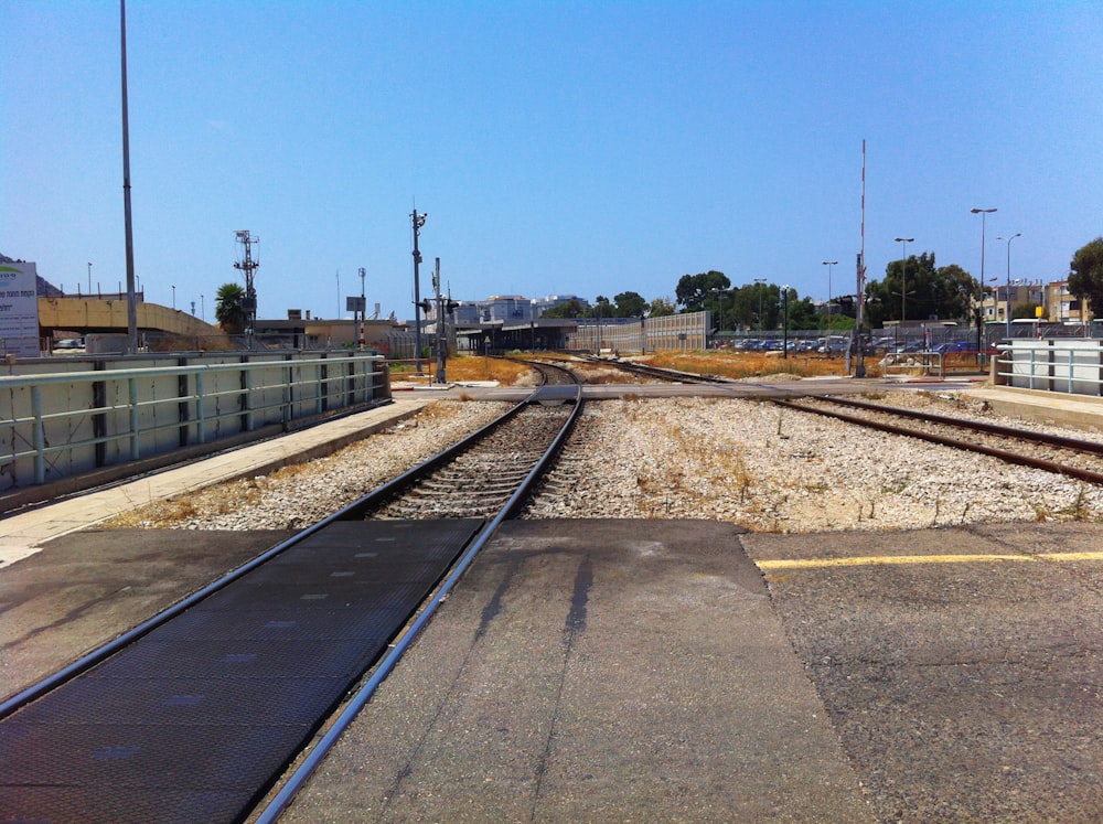 train rail near green trees under blue sky during daytime