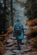 person in gray hoodie standing on brown dirt road during daytime